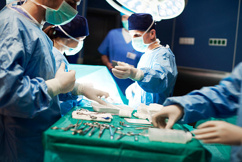 Surgeons passing basic, surgical equipment to each other