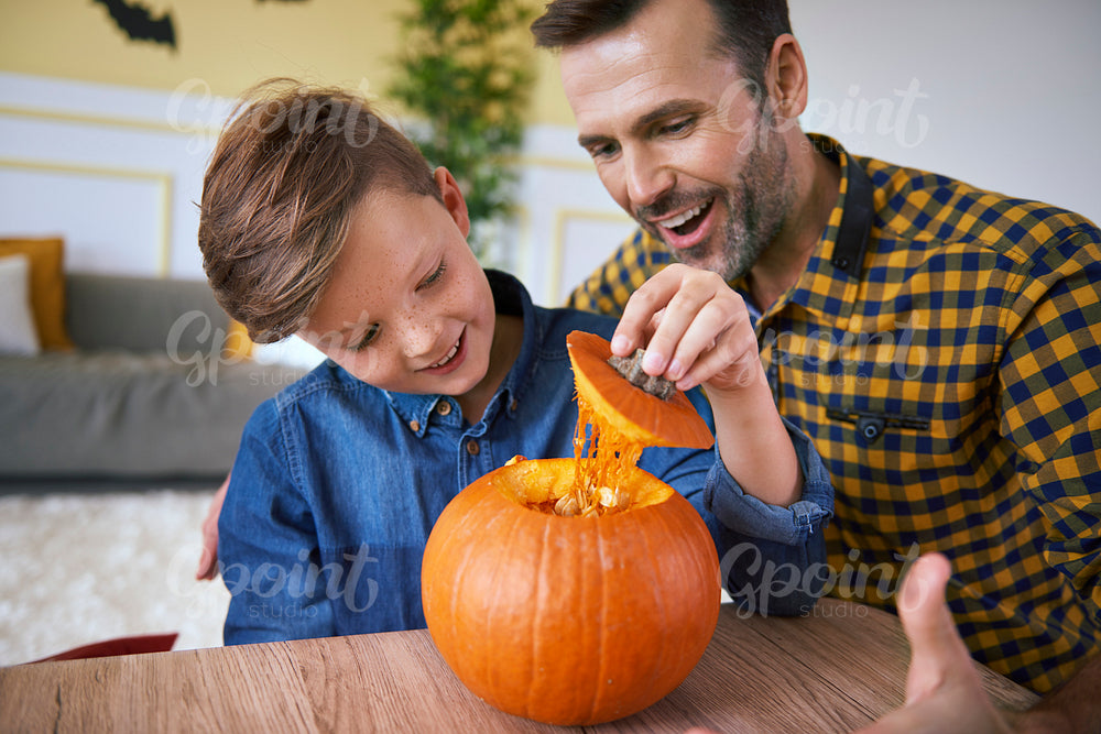Father and son making carved pumpkin