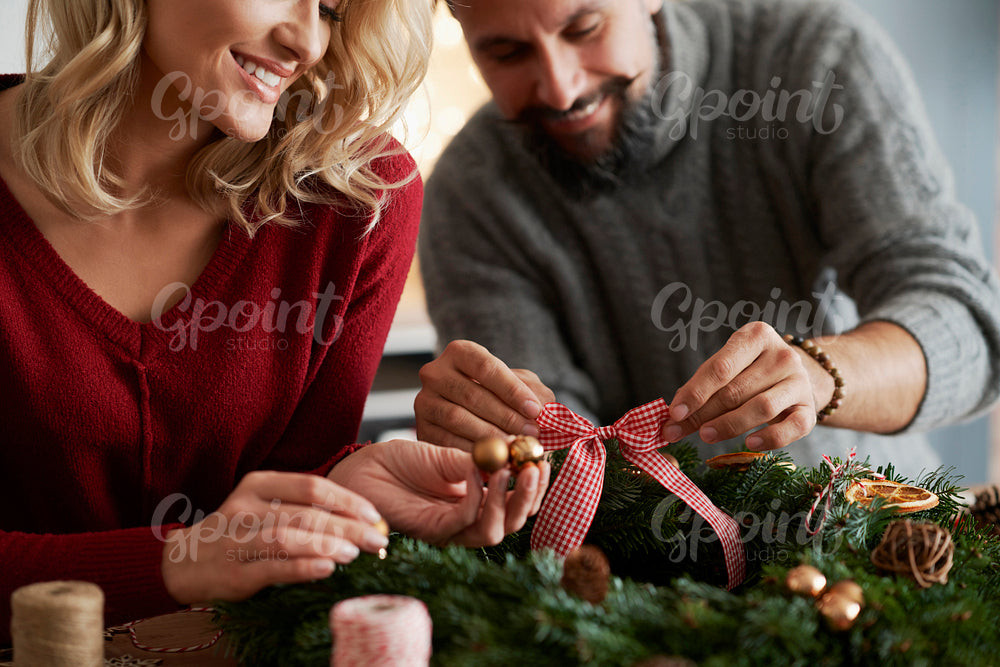 Close up of couple decorating Christmas wreath