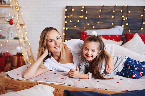 Portrait of mother and daughter spending christmas morning in bed