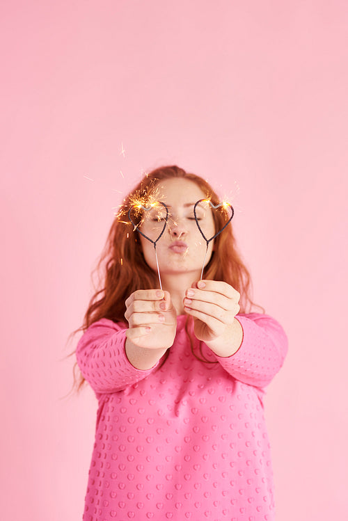 Girl holding sparklers and sending a kiss at studio shot