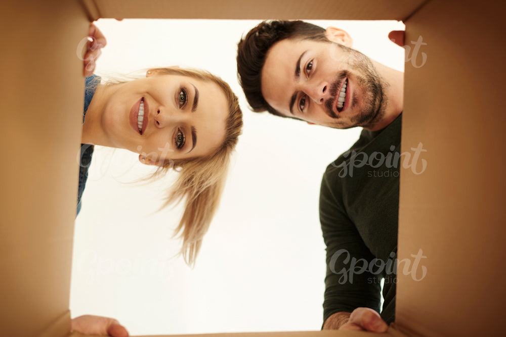 Couple looking down at camera through cardboard box