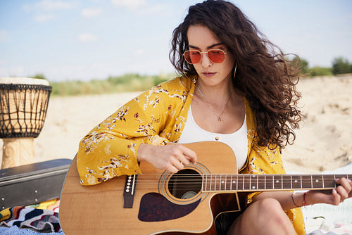 Smiling beautiful woman playing the guitar on the beach