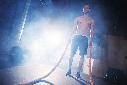 Young man doing crossfit training with ropes