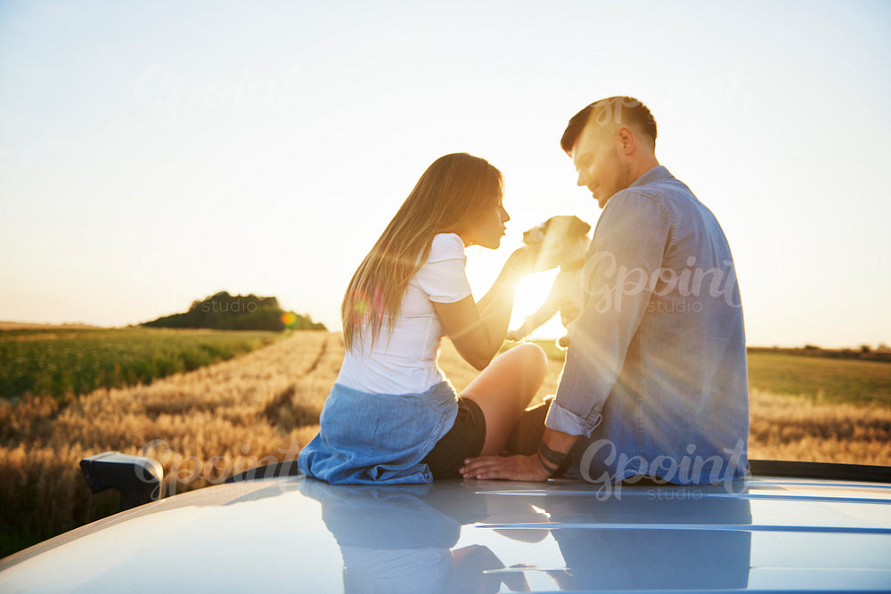 Young couple playing with dog outdoors