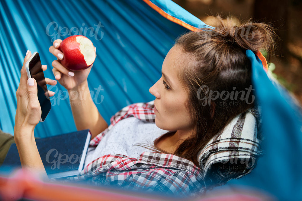 Woman relaxing on hammock and using mobile phone