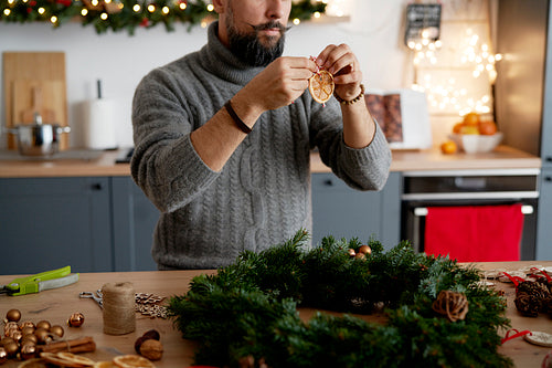 Man decorating Christmas wreath at home