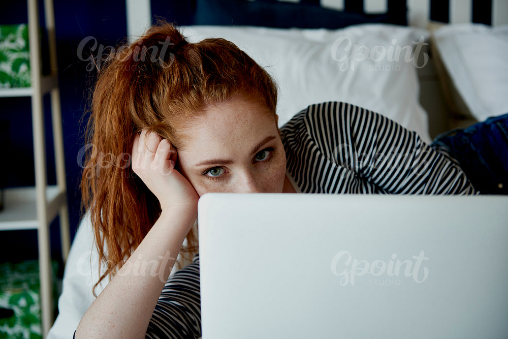Woman peeking from behind the laptop
