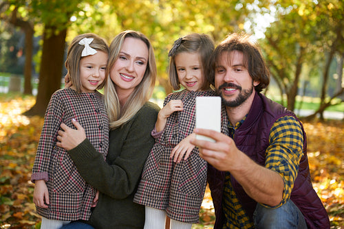 Family with two children making a selfie in autumn woods