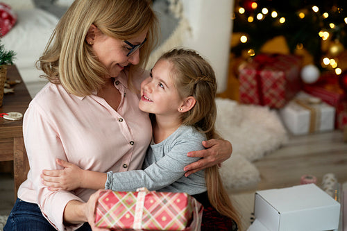 Grandmother giving her little granddaughter a Christmas gift