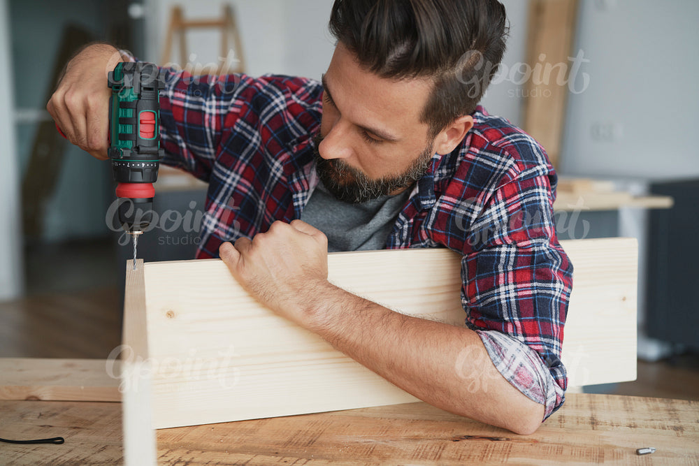 Carpenter drilling a hole in a wooden plank