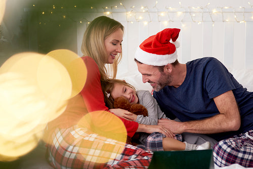 Cheerful family celebrating Xmas in bed