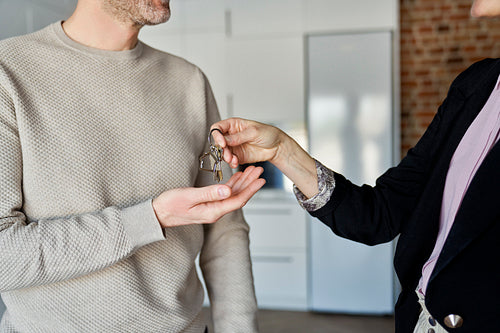 Close up of estate agent hands the keys to the man