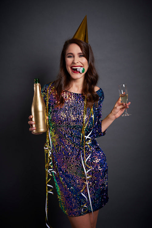 Joyful woman with party hat drinking a champagne