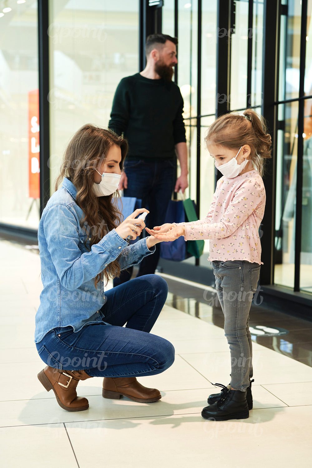 Mom disinfects her daughter's hands while shopping at the mall