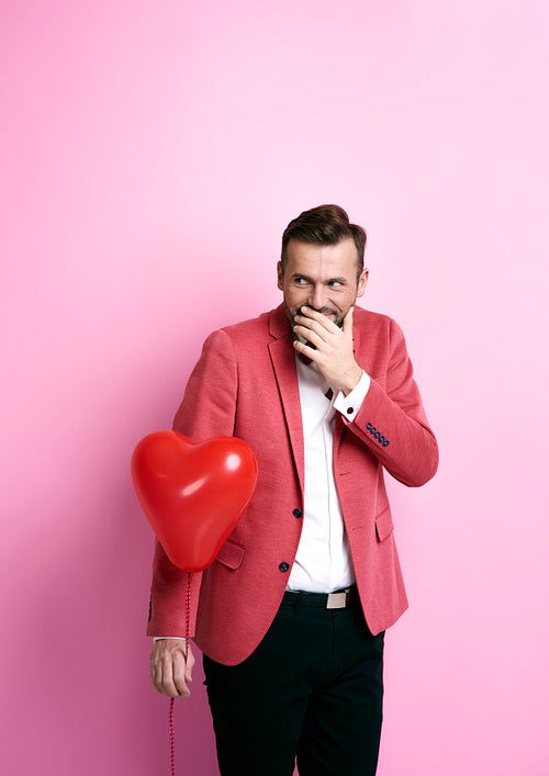 Man with heart shape balloon giggling