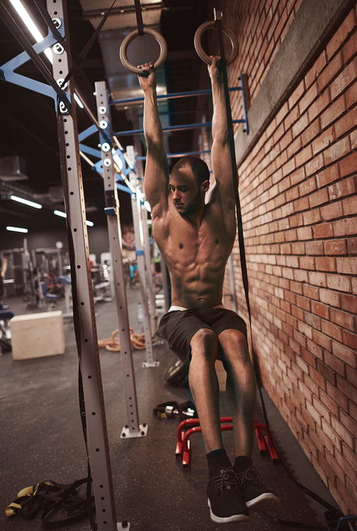 Strong body of man on gymnastic rings
