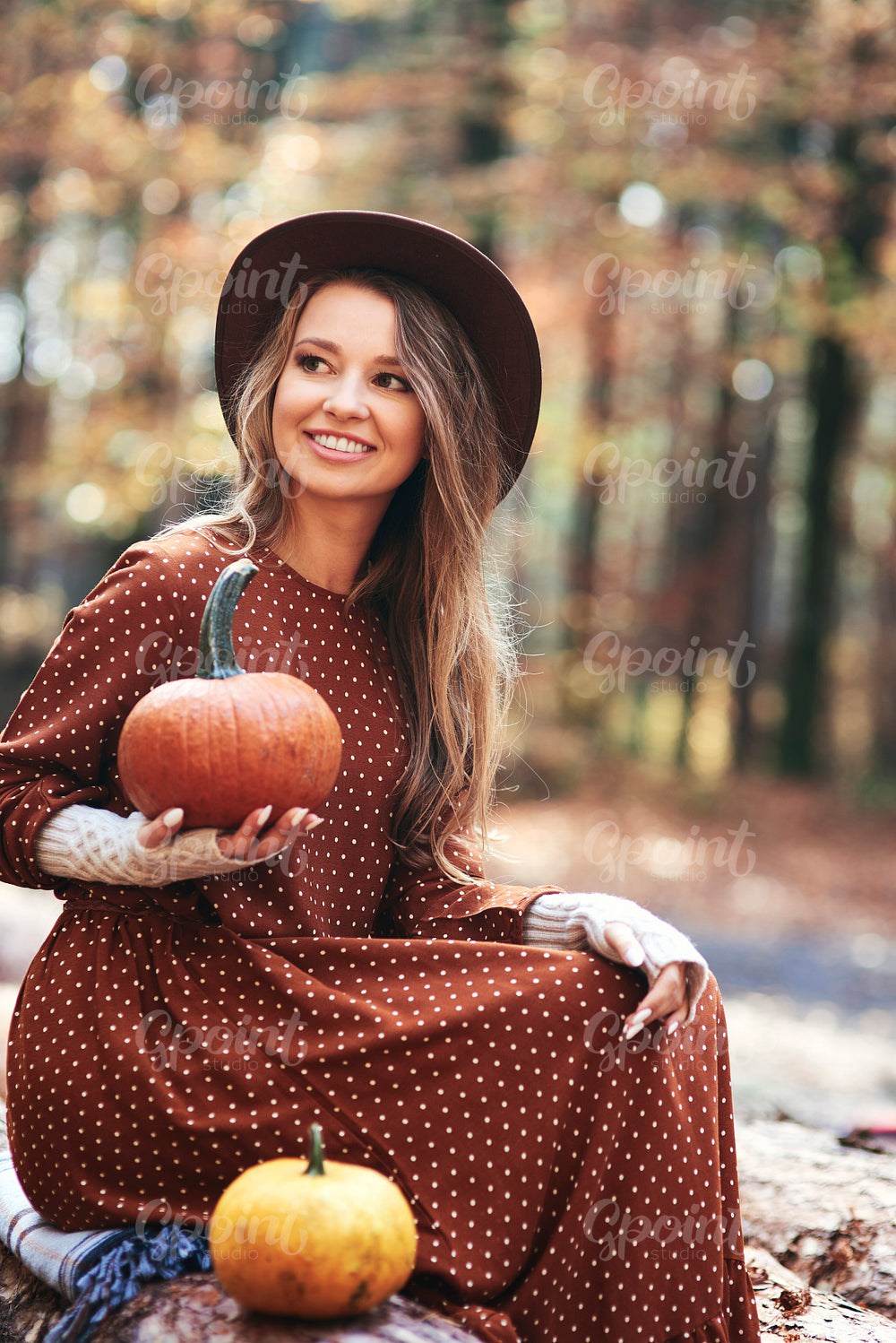 Beautiful woman holding pumpkins in autumn woods