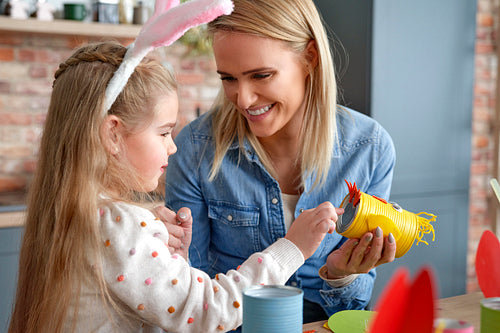 Happy mother and daughter making yellow Easter chicken
