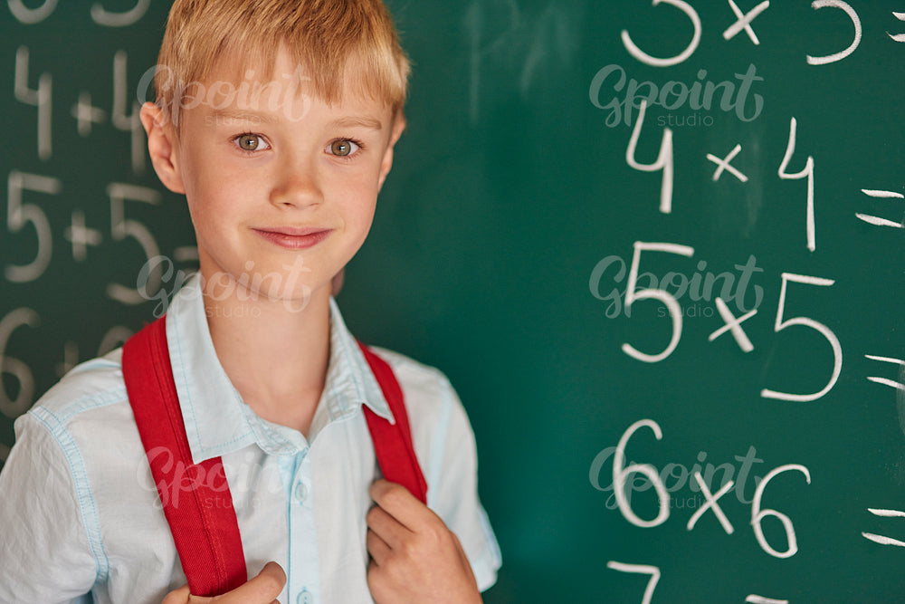 Boy standing next to the blackboard