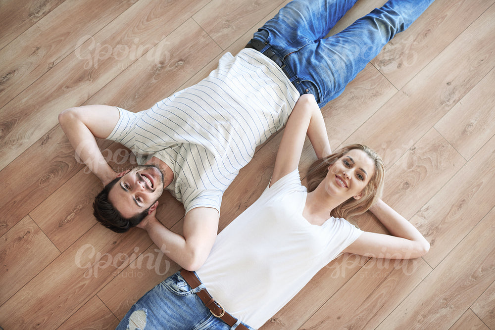 Couple with hands behind head laying on the floor
