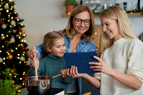 Three generations of women using a tablet in the kitchen