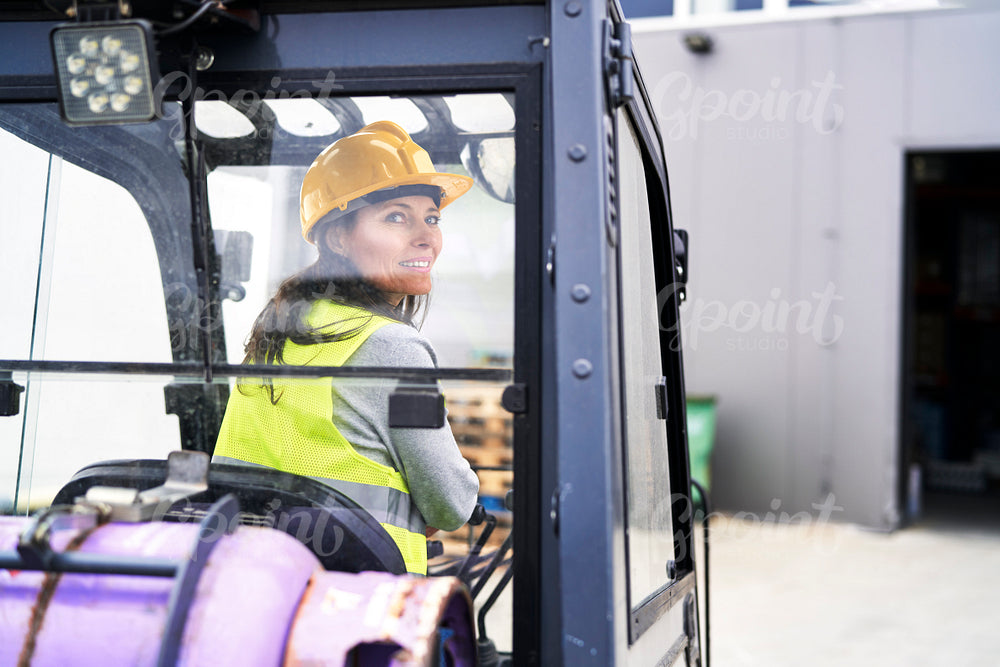 Back view of adult caucasian woman driving a forklift 