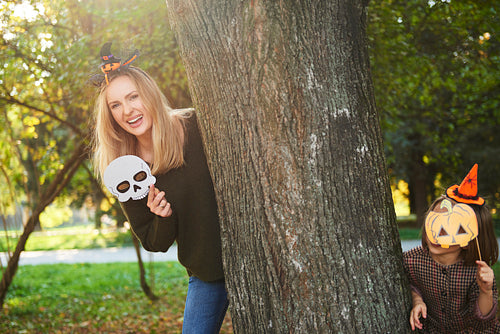 Mother and her daughter in halloween masks in autumn forest