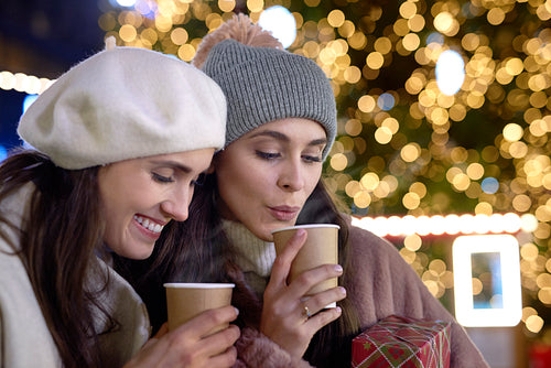 Two women drinking mulled wine on cold night