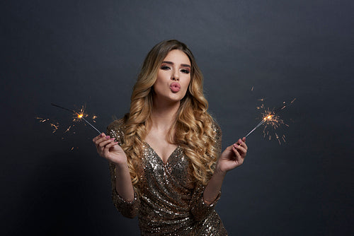 Woman with burning sparklers blowing a kiss