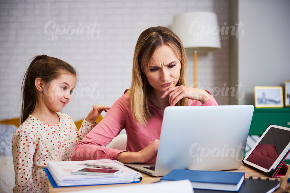 Girl disturbing her mother to work at home