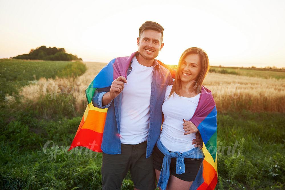 Portrait of smiling young couple with  rainbow flag