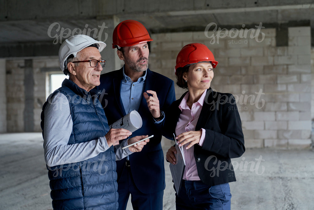 Medium shot of group of  caucasian engineers and investors standing and discussing on construction site 