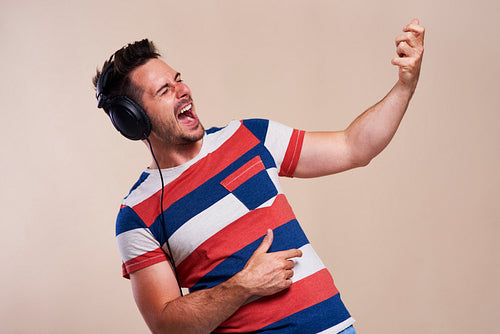 Playful man listening to music and playing air guitar