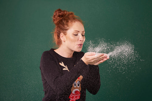 Young woman blowing fake snow
