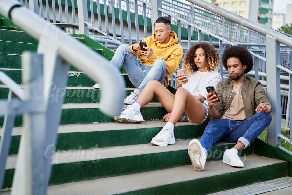 Three young people sitting on stairs with mobile phones