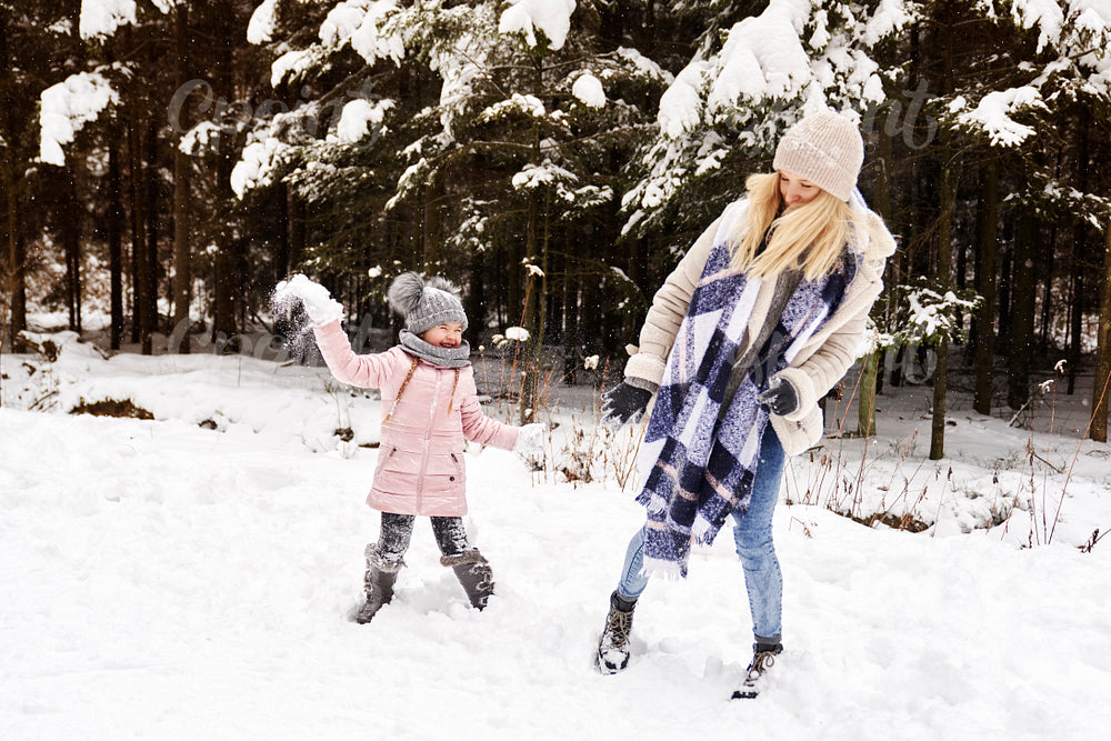 Mother and daughter having a snowball fight in the snow