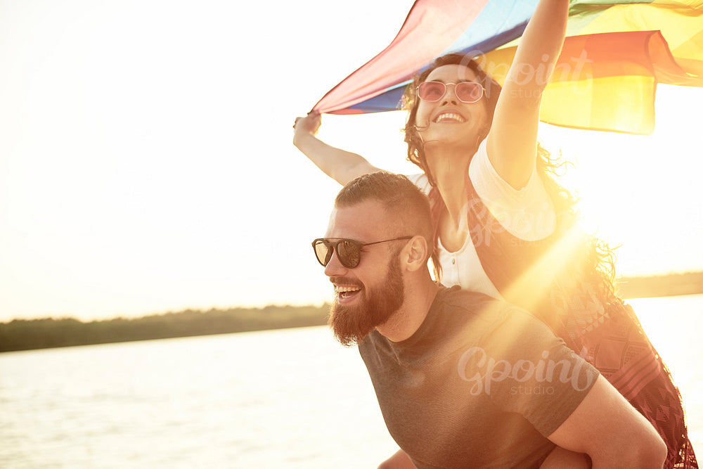 Young woman waving rainbow flag on men's arms