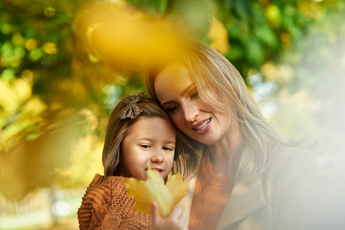 Cheerful scene of mother and daughter in autumn forest