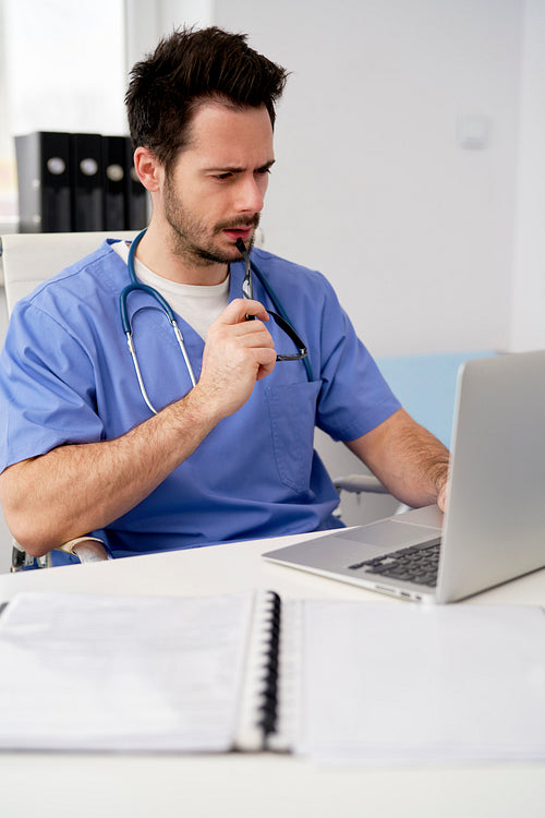 Focused doctor using laptop in doctor's office