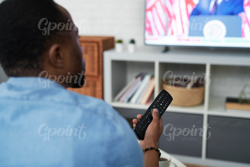 Rear view of black man watching TV