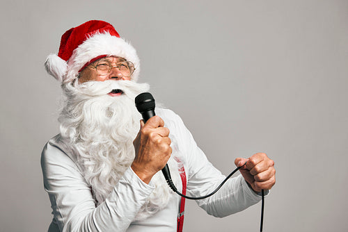 Funny caucasian Santa Claus on grey background singing Christmas songs