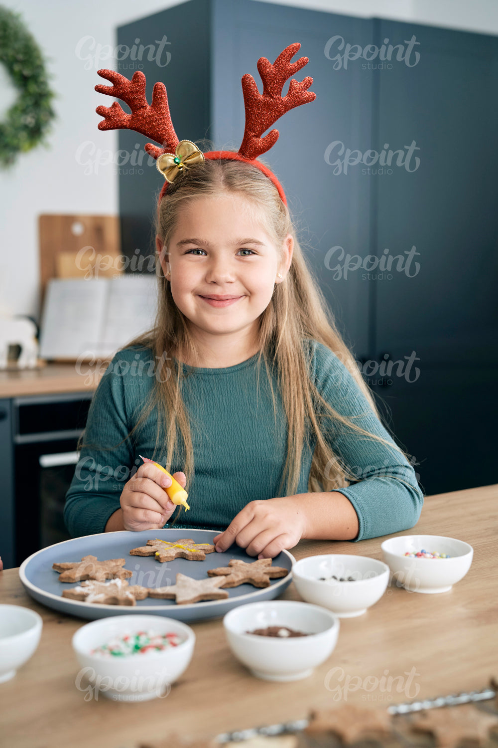 Portrait of caucasian elementary age girl decorating gingerbread cookies