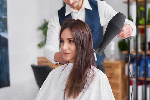 Male hairdresser using hair dryer