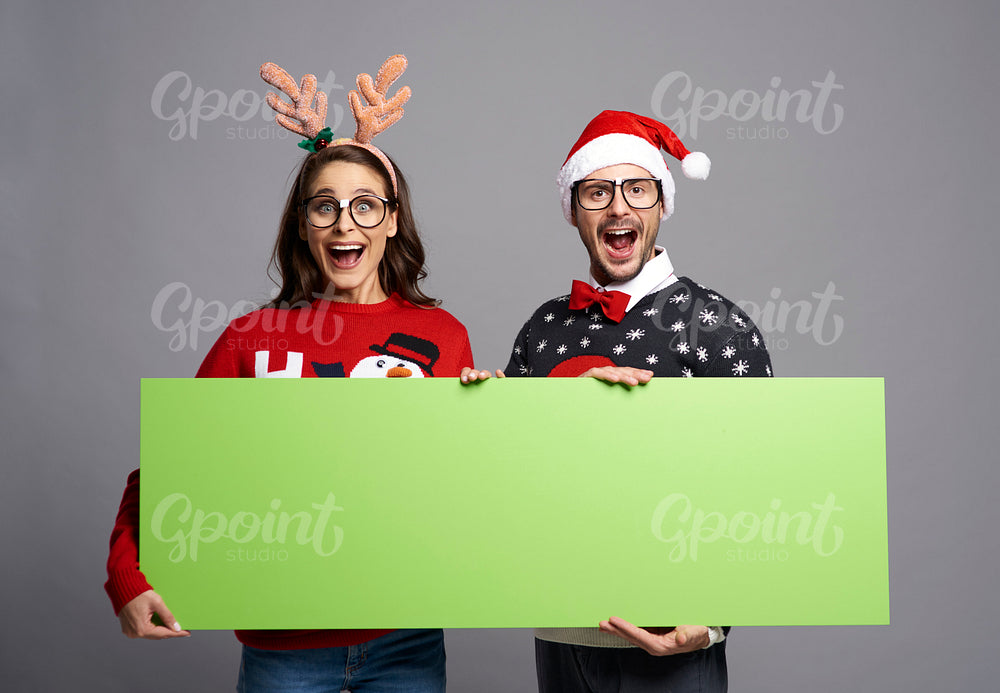 Nerd couple holding greenscreen Christmas banner with copy space