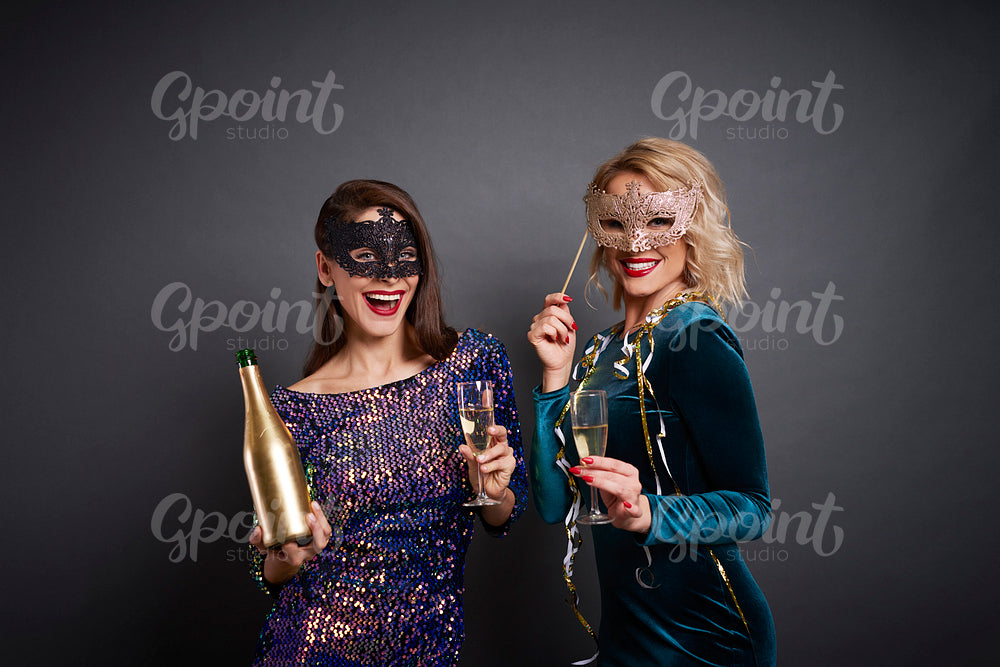 Portrait of women in masks drinking champagne