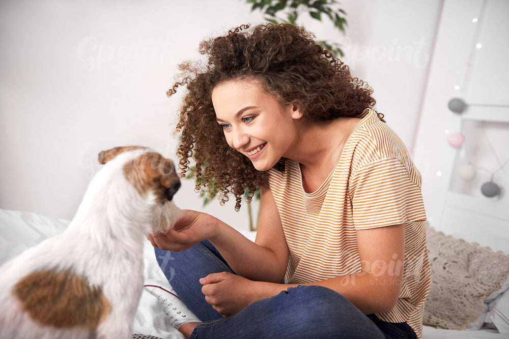 Teenage girl having fun with her dog in bedroom