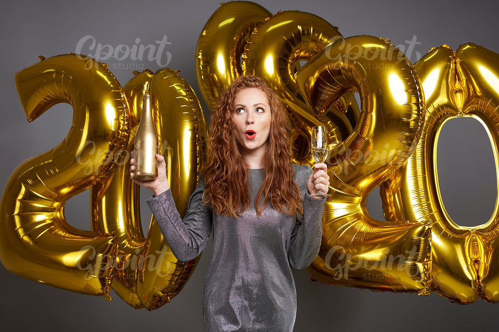 Screaming woman with golden balloon and champagne looking up