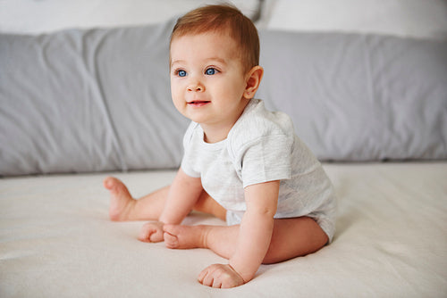 Adorable baby girl sitting on bed