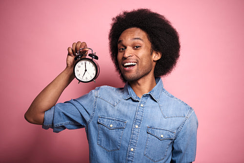 Portrait of African man with an alarm clock in hand.